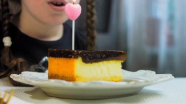 Retro tabakta cheesecake tiramisu. Altın çatal ve bıçak kullan. Kız bir dilek diliyor ve pastadaki mumu üflüyor. Doğum gününü kutluyoruz..