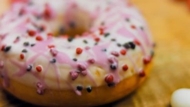 Tatlılarla süslenmiş pembe çörekler. Makro ve kaydırma atışı. Tatlı, jöleli tatlılar. Fırın ve yemek konsepti. Çeşitli renkli çörekler. Çikolata, pembe, mavi çörekler 4K, UHD.