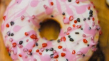 Tatlılarla süslenmiş pembe çörekler. Makro ve kaydırma atışı. Tatlı, jöleli tatlılar. Fırın ve yemek konsepti. Çeşitli renkli çörekler. Çikolata, pembe, mavi çörekler 4K, UHD.