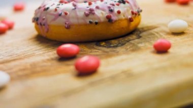 Tatlılarla süslenmiş pembe çörekler. Makro ve kaydırma atışı. Tatlı, jöleli tatlılar. Fırın ve yemek konsepti. Çeşitli renkli çörekler. Çikolata, pembe, mavi çörekler 4K, UHD.