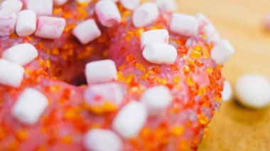 Marshmello ile süslenmiş pembe çörekler. Makro ve kaydırma atışı. Fırın ve yemek konsepti. Çeşitli renkli çörekler. Çikolata, pembe, mavi çörekler 4K, UHD.