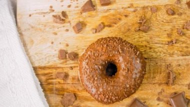 Çikolatalı çörekler çikolata parçalarıyla süslenmiş. Donutlar doğal çikolatayla süslenmiş bir kağıdın üzerinde. Makro ve kaydırma atışı. Fırın ve yemek konsepti. Çeşitli renkli çörekler. Çikolata, pembe