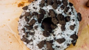 Oeo bisküvileriyle süslenmiş çikolatalı çörekler. Donutlar doğal çikolatayla süslenmiş bir kağıdın üzerinde. Makro ve kaydırma atışı. Fırın ve yemek konsepti. Çeşitli renkli çörekler. Çikolata.