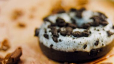 Oeo bisküvileriyle süslenmiş çikolatalı çörekler. Donutlar doğal çikolatayla süslenmiş bir kağıdın üzerinde. Makro ve kaydırma atışı. Fırın ve yemek konsepti. Çeşitli renkli çörekler. Çikolata.