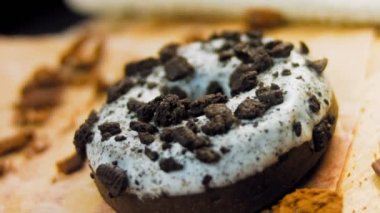 Oeo bisküvileriyle süslenmiş çikolatalı çörekler. Donutlar doğal çikolatayla süslenmiş bir kağıdın üzerinde. Makro ve kaydırma atışı. Fırın ve yemek konsepti. Çeşitli renkli çörekler. Çikolata.