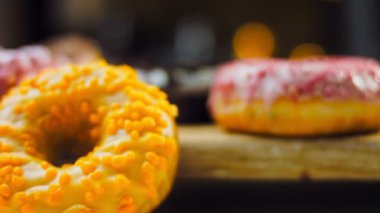 Çikolata, marşmelov ve retro pişirme tepsisindeki şekerli çörekler. Donutlar doğal çikolatayla süslenmiş bir kağıdın üzerinde. Makro ve kaydırma atışı. Çeşitli renkli çörekler. Çikolata, pembe, mavi çörekler