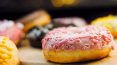 Çikolata, marşmelov ve retro pişirme tepsisindeki şekerli çörekler. Donutlar doğal çikolatayla süslenmiş bir kağıdın üzerinde. Makro ve kaydırma atışı. Çeşitli renkli çörekler. Çikolata, pembe, mavi çörekler