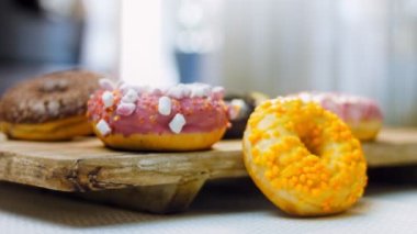 Çikolata, marşmelov ve retro pişirme tepsisindeki şekerli çörekler. Donutlar doğal çikolatayla süslenmiş bir kağıdın üzerinde. Makro ve kaydırma atışı. Çeşitli renkli çörekler. Çikolata, pembe, mavi çörekler