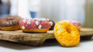 Çikolata, marşmelov ve retro pişirme tepsisindeki şekerli çörekler. Donutlar doğal çikolatayla süslenmiş bir kağıdın üzerinde. Makro ve kaydırma atışı. Çeşitli renkli çörekler. Çikolata, pembe, mavi çörekler