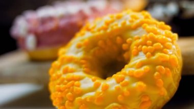 Çikolata, marşmelov ve retro pişirme tepsisindeki şekerli çörekler. Donutlar doğal çikolatayla süslenmiş bir kağıdın üzerinde. Makro ve kaydırma atışı. Çeşitli renkli çörekler. Çikolata, pembe, mavi çörekler