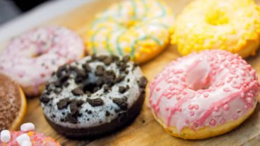 Çikolata, marşmelov ve retro pişirme tepsisindeki şekerli çörekler. Donutlar doğal çikolatayla süslenmiş bir kağıdın üzerinde. Makro ve kaydırma atışı. Çeşitli renkli çörekler. Çikolata, pembe, mavi çörekler