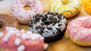 Çikolata, marşmelov ve retro pişirme tepsisindeki şekerli çörekler. Donutlar doğal çikolatayla süslenmiş bir kağıdın üzerinde. Makro ve kaydırma atışı. Çeşitli renkli çörekler. Çikolata, pembe, mavi çörekler