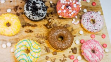 Çikolata, marşmelov ve retro pişirme tepsisindeki şekerli çörekler. Donutlar doğal çikolatayla süslenmiş bir kağıdın üzerinde. Makro ve kaydırma atışı. Çeşitli renkli çörekler. Çikolata, pembe, mavi çörekler