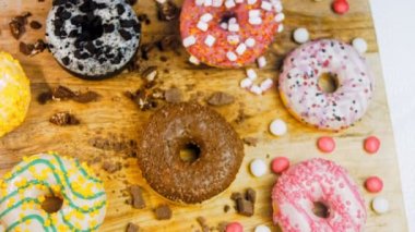 Çikolata, marşmelov ve retro pişirme tepsisindeki şekerli çörekler. Donutlar doğal çikolatayla süslenmiş bir kağıdın üzerinde. Makro ve kaydırma atışı. Çeşitli renkli çörekler. Çikolata, pembe, mavi çörekler