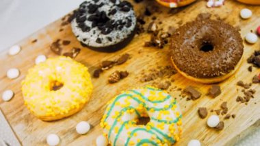 Çikolata, marşmelov ve retro pişirme tepsisindeki şekerli çörekler. Donutlar doğal çikolatayla süslenmiş bir kağıdın üzerinde. Makro ve kaydırma atışı. Çeşitli renkli çörekler. Çikolata, pembe, mavi çörekler