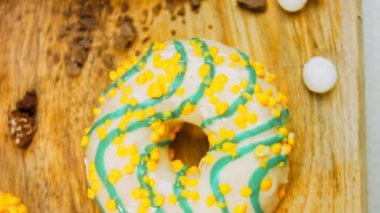 Çikolata, marşmelov ve retro pişirme tepsisindeki şekerli çörekler. Donutlar doğal çikolatayla süslenmiş bir kağıdın üzerinde. Makro ve kaydırma atışı. Çeşitli renkli çörekler. Çikolata, pembe, mavi çörekler