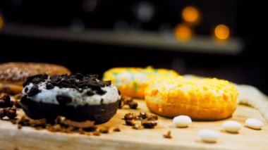 Çikolata, marşmelov ve retro pişirme tepsisindeki şekerli çörekler. Donutlar doğal çikolatayla süslenmiş bir kağıdın üzerinde. Makro ve kaydırma atışı. Çeşitli renkli çörekler. Çikolata, pembe, mavi çörekler