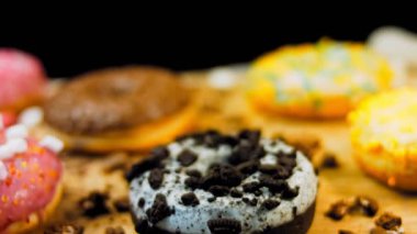 Çikolata, marşmelov ve retro pişirme tepsisindeki şekerli çörekler. Donutlar doğal çikolatayla süslenmiş bir kağıdın üzerinde. Makro ve kaydırma atışı. Çeşitli renkli çörekler. Çikolata, pembe, mavi çörekler