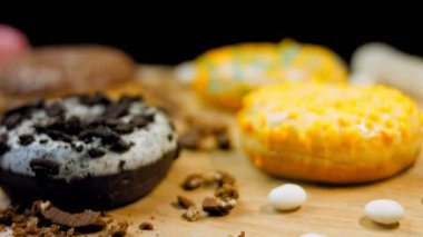 Çikolata, marşmelov ve retro pişirme tepsisindeki şekerli çörekler. Donutlar doğal çikolatayla süslenmiş bir kağıdın üzerinde. Makro ve kaydırma atışı. Çeşitli renkli çörekler. Çikolata, pembe, mavi çörekler