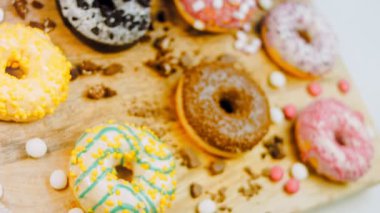 Çikolata, marşmelov ve retro pişirme tepsisindeki şekerli çörekler. Donutlar doğal çikolatayla süslenmiş bir kağıdın üzerinde. Makro ve kaydırma atışı. Çeşitli renkli çörekler. Çikolata, pembe, mavi çörekler