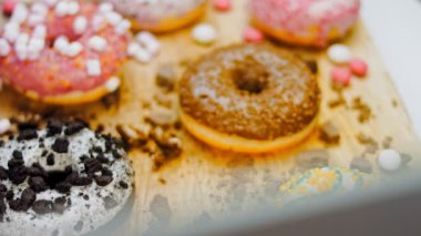 Çikolata, marşmelov ve retro pişirme tepsisindeki şekerli çörekler. Donutlar doğal çikolatayla süslenmiş bir kağıdın üzerinde. Makro ve kaydırma atışı. Çeşitli renkli çörekler. Çikolata, pembe, mavi çörekler