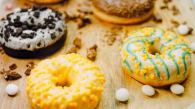 Çikolata, marşmelov ve retro pişirme tepsisindeki şekerli çörekler. Donutlar doğal çikolatayla süslenmiş bir kağıdın üzerinde. Makro ve kaydırma atışı. Çeşitli renkli çörekler. Çikolata, pembe, mavi çörekler