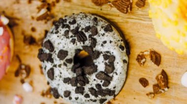 Çikolata, marşmelov ve retro pişirme tepsisindeki şekerli çörekler. Donutlar doğal çikolatayla süslenmiş bir kağıdın üzerinde. Makro ve kaydırma atışı. Çeşitli renkli çörekler. Çikolata, pembe, mavi çörekler
