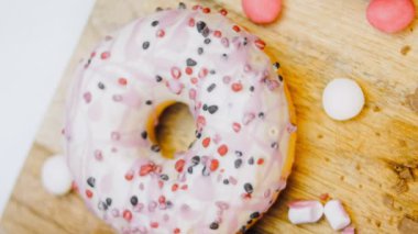 Çikolata, marşmelov ve retro pişirme tepsisindeki şekerli çörekler. Donutlar doğal çikolatayla süslenmiş bir kağıdın üzerinde. Makro ve kaydırma atışı. Çeşitli renkli çörekler. Çikolata, pembe, mavi çörekler