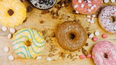 Çikolata, marşmelov ve retro pişirme tepsisindeki şekerli çörekler. Donutlar doğal çikolatayla süslenmiş bir kağıdın üzerinde. Makro ve kaydırma atışı. Çeşitli renkli çörekler. Çikolata, pembe, mavi çörekler