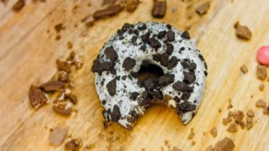 Donut 'ın ağız şeklinde bir ısırığı var. Oeo bisküvileriyle süslenmiş çikolatalı çörekler. Donutlar doğal çikolatayla süslenmiş bir kağıdın üzerinde. Makro ve kaydırma atışı. Fırın ve gıda konsepti