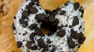 Donut 'ın ağız şeklinde bir ısırığı var. Oeo bisküvileriyle süslenmiş çikolatalı çörekler. Donutlar doğal çikolatayla süslenmiş bir kağıdın üzerinde. Makro ve kaydırma atışı. Fırın ve gıda konsepti