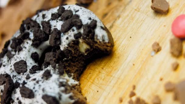 多努特有一个嘴巴状的咬痕 巧克力甜甜圈 上面装饰着一些意大利饼干 甜甜圈在用天然巧克力装饰的纸上 宏观和滑翔机射击 面包店和食品概念 — 图库视频影像