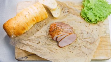 Fransız ekmeğiyle dilimlenmiş domuz filetosu. Sosis retro-stil yemek tepsisinde ve yemek kağıdında. Yavaş çekim kaydırağın üzerinde. Taze marul yaprakları da kullanıyoruz..