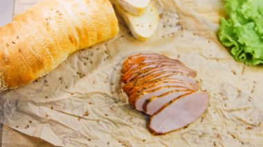 Fransız ekmeğiyle dilimlenmiş domuz filetosu. Sosis retro-stil yemek tepsisinde ve yemek kağıdında. Yavaş çekim kaydırağın üzerinde. Taze marul yaprakları da kullanıyoruz..