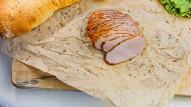 Fransız ekmeğiyle dilimlenmiş domuz filetosu. Sosis retro-stil yemek tepsisinde ve yemek kağıdında. Yavaş çekim kaydırağın üzerinde. Taze marul yaprakları da kullanıyoruz..