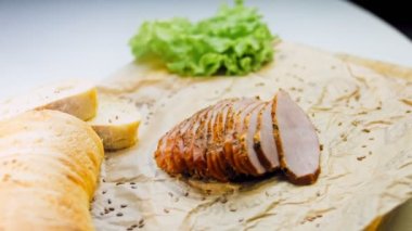 Fransız ekmeğiyle dilimlenmiş domuz filetosu. Sosis retro-stil yemek tepsisinde ve yemek kağıdında. Yavaş çekim kaydırağın üzerinde. Taze marul yaprakları da kullanıyoruz..