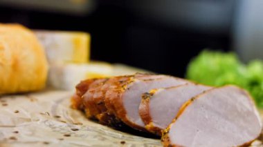 Fransız ekmeğiyle dilimlenmiş domuz filetosu. Sosis retro-stil yemek tepsisinde ve yemek kağıdında. Yavaş çekim kaydırağın üzerinde. Taze marul yaprakları da kullanıyoruz..