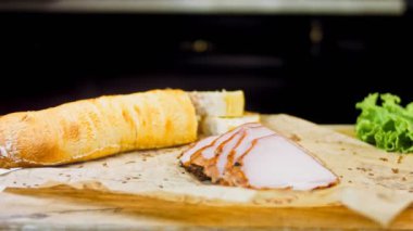 Fransız ekmeğiyle dilimlenmiş domuz filetosu. Sosis retro-stil yemek tepsisinde ve yemek kağıdında. Yavaş çekim kaydırağın üzerinde. Taze marul yaprakları da kullanıyoruz..