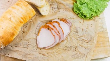 Fransız ekmeğiyle dilimlenmiş domuz filetosu. Sosis retro-stil yemek tepsisinde ve yemek kağıdında. Yavaş çekim kaydırağın üzerinde. Taze marul yaprakları da kullanıyoruz..