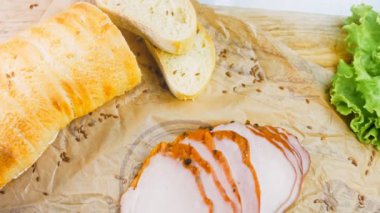 Fransız ekmeğiyle dilimlenmiş domuz filetosu. Sosis retro-stil yemek tepsisinde ve yemek kağıdında. Yavaş çekim kaydırağın üzerinde. Taze marul yaprakları da kullanıyoruz..