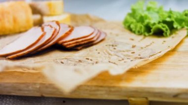 Fransız ekmeğiyle dilimlenmiş domuz filetosu. Sosis retro-stil yemek tepsisinde ve yemek kağıdında. Yavaş çekim kaydırağın üzerinde. Taze marul yaprakları da kullanıyoruz..