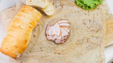 Fransız ekmeğiyle dilimlenmiş domuz pastırması. Sosis retro-stil yemek tepsisinde ve yemek kağıdında. Yavaş çekim kaydırağın üzerinde. Taze marul yaprakları da kullanıyoruz..