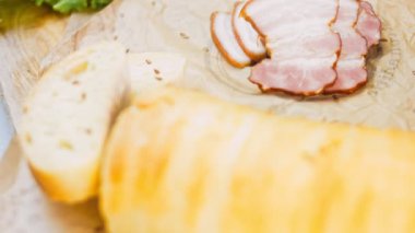 Fransız ekmeğiyle dilimlenmiş domuz pastırması. Sosis retro-stil yemek tepsisinde ve yemek kağıdında. Yavaş çekim kaydırağın üzerinde. Taze marul yaprakları da kullanıyoruz..