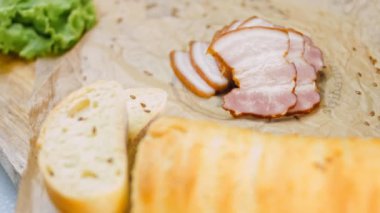 Fransız ekmeğiyle dilimlenmiş domuz pastırması. Sosis retro-stil yemek tepsisinde ve yemek kağıdında. Yavaş çekim kaydırağın üzerinde. Taze marul yaprakları da kullanıyoruz..