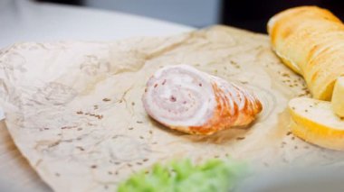 Fransız ekmeğiyle dilimlenmiş sosisli börek. Sosis retro-stil yemek tepsisinde ve yemek kağıdında. Yavaş çekim kaydırağın üzerinde. Taze marul yaprakları da kullanıyoruz..