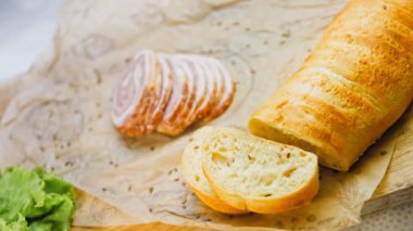 Fransız ekmeğiyle dilimlenmiş sosisli börek. Sosis retro-stil yemek tepsisinde ve yemek kağıdında. Yavaş çekim kaydırağın üzerinde. Taze marul yaprakları da kullanıyoruz..