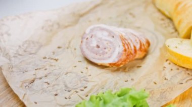 Fransız ekmeğiyle dilimlenmiş sosisli börek. Sosis retro-stil yemek tepsisinde ve yemek kağıdında. Yavaş çekim kaydırağın üzerinde. Taze marul yaprakları da kullanıyoruz..