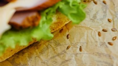 Fransız ekmeği, peynir, marul ve sosisli sandviç. Kaydırma atışı. Arka planda eski bir fırın tepsisi ve yemek kağıdı var..