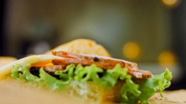 Fransız ekmeği, peynir, marul ve sosisli sandviç. Kaydırma atışı. Arka planda eski bir fırın tepsisi ve yemek kağıdı var..