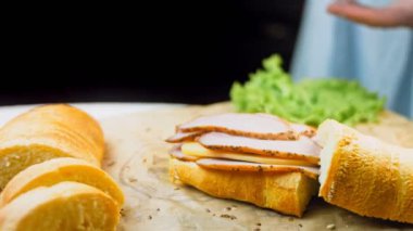 Şef, sanvich 'in üzerine Fransız ekmeği, peynir, marul ve sosisle kalp şeklinde kızarmış bir yumurta bırakıyor. Kaydırıcı atışı.